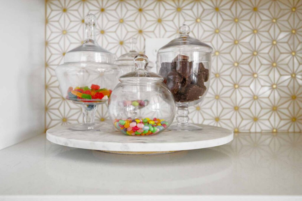 Kitchen detail with jars of candy against a white and gold backsplash