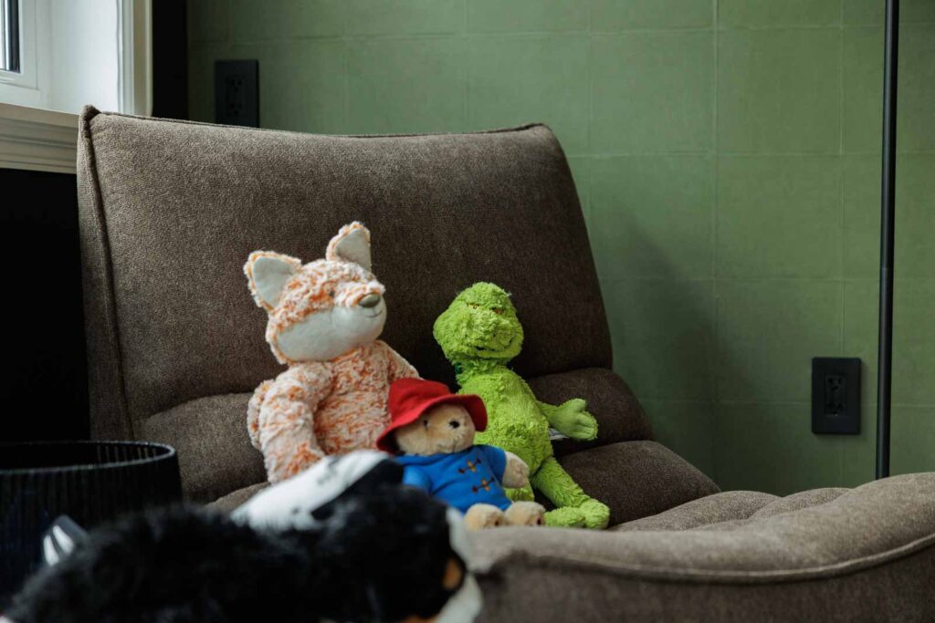 Guest bedroom with green walls and plushie toys sitting on chair