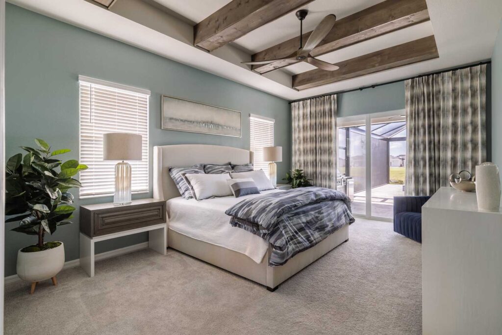 Primary bedroom with wooden beams in ceiling and light-blue walls and soft bedding