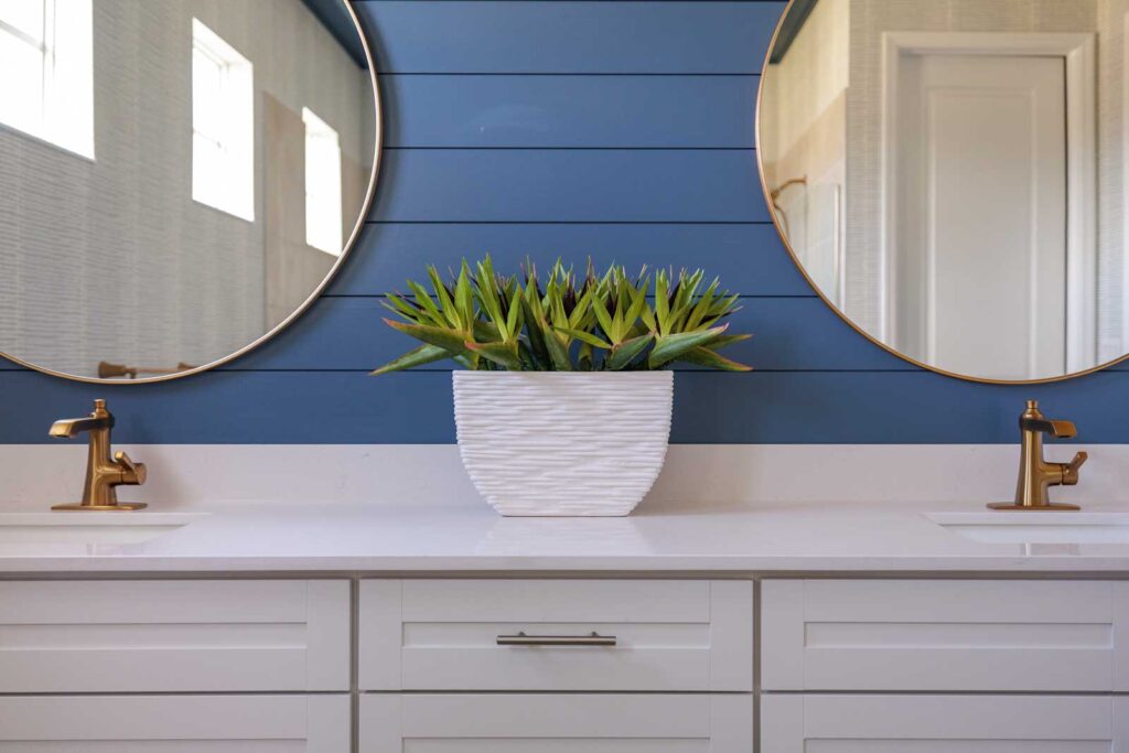 Primary bath detail of sink with blue shiplap wall and round mirrors