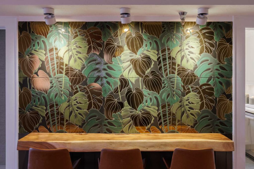 Dining room detail of built-in bar with tropical tiled wall, live-edge barter, and leather-backed stools